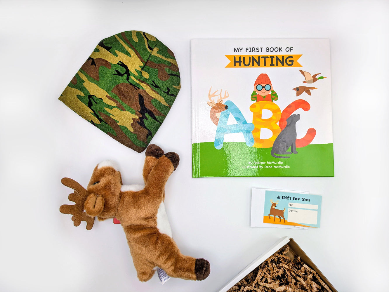 My First Book of Hunting ABC, camouflage hat, plush deer, and gift tag on white surface.